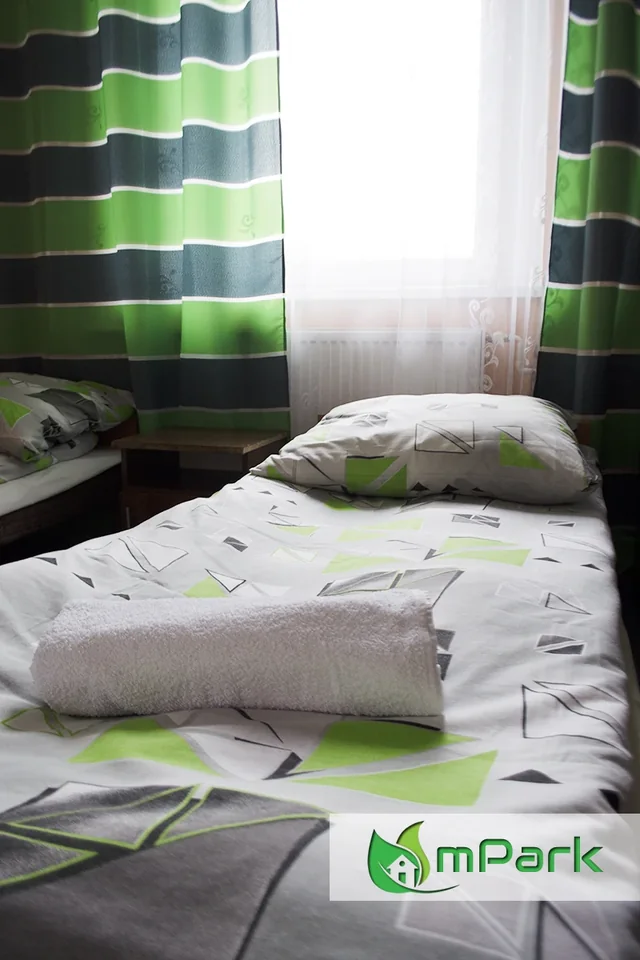 Pokój Grupy mPark — łóżko i zielone zasłony